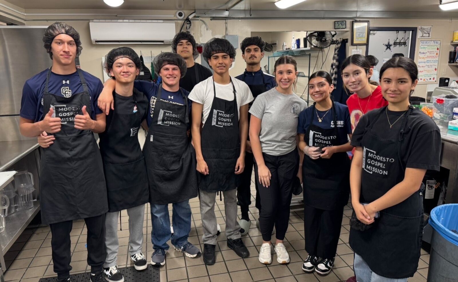 Central Catholic High School students in aprons serving a meal at a community kitchen